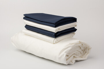 Stack of clean white and blue bed sheets on white  background, closeup.