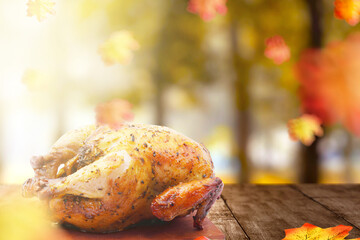 Roasted turkey on wooden table with autumn leaves