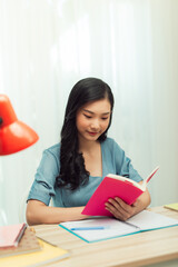 Naklejka premium Focused school girl studying with books preparing for test exam writing essay doing homework at home