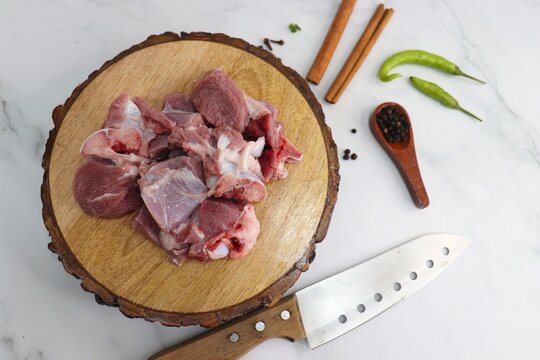 Fresh raw goat meat or mutton or lamb pieces. Preparation for Indian mutton curry. Spice at the background such as cinnamon sticks, red chili powder, black pepper & coriander. Copy space.
