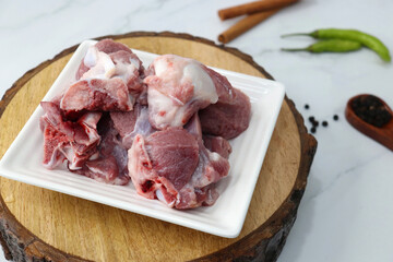 Fresh raw goat meat or mutton or lamb pieces. Preparation for Indian mutton curry. Spice at the background such as cinnamon sticks, red chili powder, black pepper & coriander. Copy space.