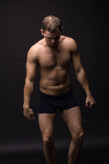 Fototapeta na wymiar Handsome man in underwear on the black background. Muscular and athletic. Underwear man portrait. Male underwear model in studio 