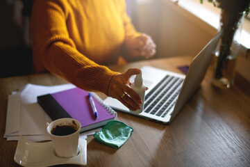 Close up of woman disinfects the laptop  with spray disinfectant liquid. Coronavirus covid-19...