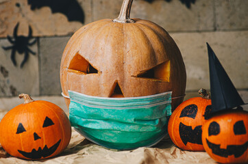 Close up view of Halloween pumpkin lantern wearing a medical facial mask as a symbol of disease control and virus infection and coronavirus or covid-19
