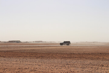 4x4 crossing the desert with a camp in the background