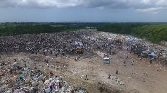 People collect and sort waste at Duquesa landfill. Aerial forward view