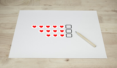 White paper with level satisfaction red heart and pencil on wooden table,Choosing level satisfaction customer service feedback concept