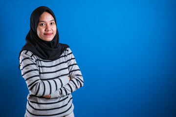 Fototapeta na wymiar Asian muslim college student girl wearing hijab smiling friendly with arms crossed