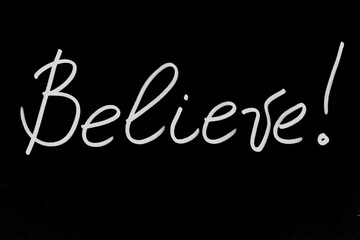 Handwritten inscription Believe in white marker on a black background