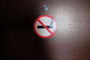 No smoking sign stuck on the wooden door of the hotel room. The crossed out cigarette. Concept...
