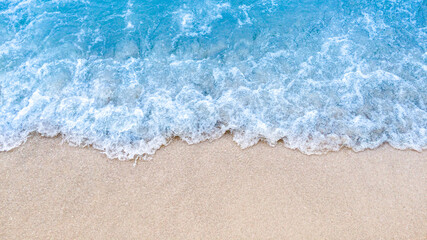 Naklejka na ściany i meble Wave of blue ocean on sandy beach background