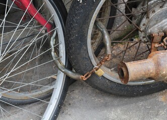 Rusty chain and lock bicycle wheel and motorcycle wheel.