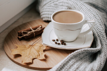 cup of coffee with coffee beans and cinnamon sticks on a wooden tray