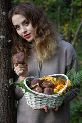 Girl in the forest with a basket full of mushrooms. Autumn photo.