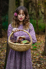Girl in the forest in a dress with a floral pattern with a basket full of mushrooms. Photo in retro style.