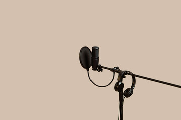 Items for podcasting: professional microphone and earphones isolated on beige  background. Place...