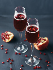 Christmas Mimosa cocktail with champagne and pomegranate on a dark table