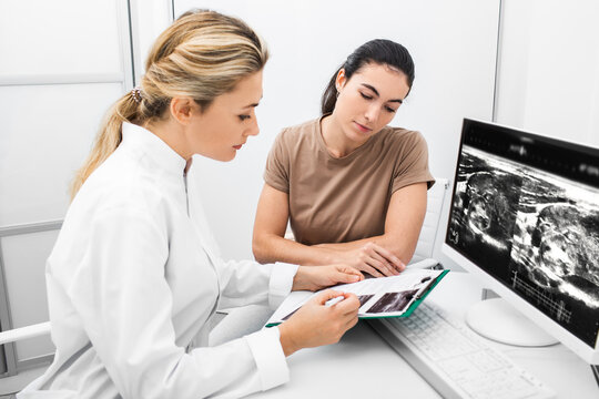 Endocrinologist consulting the woman, doctor analyzes the ultrasound of the patient's thyroid gland. Treatment of thyrotoxicosis, and hypothyroidism