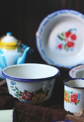 Enamel set kitchen with flowery pattern. Vintage look, on dark wooden background. 