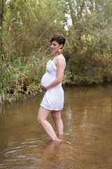 young pregnant woman sitting on a bench in the field.