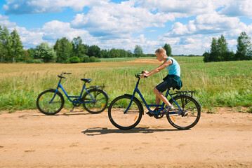The boy rides a bike against the backdrop of a beautiful countryside