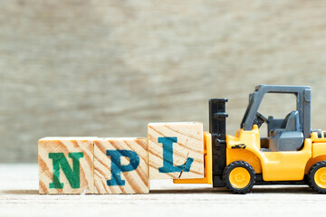 Toy forklift hold letter block l to complete word NPL (Abbbreviation of Non Performing Loan, Non-Patent Literature) on wood background