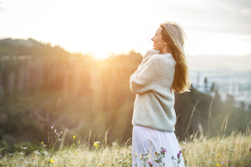 Happy woman enjoying sunset stay on the green grass on the forest peak of mountain. Travel, Summer, Holidays, Journey, Trip,.
