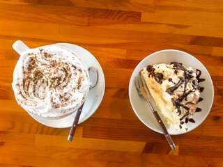 Cappuccino coffee. A Cup of cappuccino, latte stands on a wooden table with a sweet slice of cake...