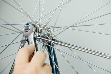 close up men's hands repair the wheel of a Bicycle, a man unscrews the wheel with a wrench