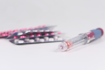 Obraz premium Insulin pen and pills on white background with copy space 