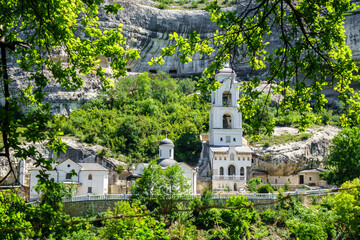 The buildings of the Assumption Cave Monastery in a scenic frame made of tree branches, Bakhchysarai, Crimea