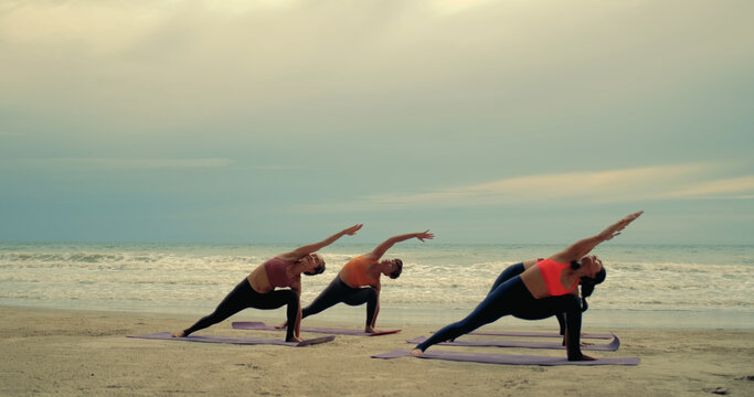 Professional group females yoga practice in class on mat stretching