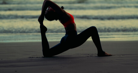 Silhouette woman doing yoga pose on mat outdoor stretching exercise