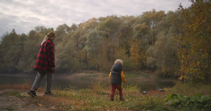 little boy and mother are playing with doves in forest, happy entertainment and having fun at nature