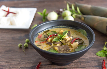 Chicken green curry with bamboo shoots and blood pudding (Kaeng kheiyw hwan) on dark wooden background with Thai tradition food served with steamed rice. Thai food very popular