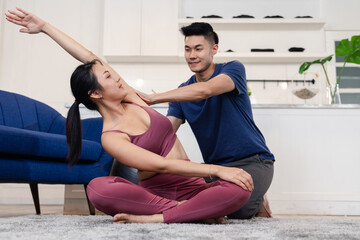 Young asian girl beginning yoga practice with private teacher at home class. Working out with professional male yogi instructor. Fitness, Yoga practice exercise class concept.