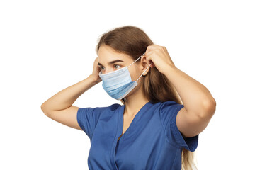 Beautiful young woman doctor surgeon putting on a protective disposable face mask isolated on white background. Virus protection concept. The modern viral threat of coronavirus