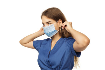 Beautiful young woman doctor surgeon putting on a protective disposable face mask isolated on white background. Virus protection concept. The modern viral threat of coronavirus