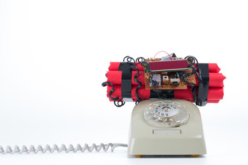 Studio photo of old vintage rotary telephone with time bomb on top, bright background.