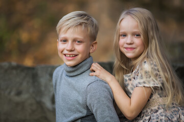 Fototapeta na wymiar Portrait of brother and sister. Happy children outdoors. Two kids having fun in autumn park. Cute little brother and sister on a walk in autumn day. Family, fashion, vacation and lifestyle concept.