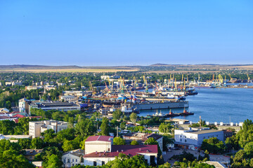 Fototapeta na wymiar Panorama of sea port with working cranes, docks & ships. Shot in Kerch, Crimea
