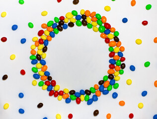 Top round frame of a colorful candy covered with chocolate on a white background with space for text