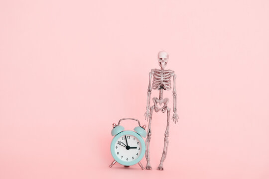 skeleton and alarm clock, deadline concept on a pink background