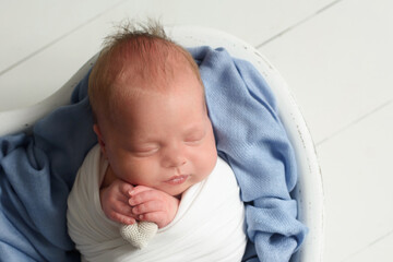 Cute llitlenewborn baby with blue blanket sleeping on soft blue coverlet
