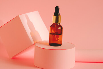 glass bottle with cosmetic product with pipette on a pink pedestal on a pink background