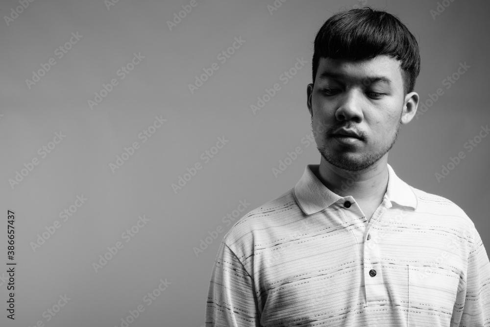 Wall mural Portrait of young Asian man against gray background - Wall murals