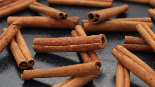 heap of cinnamon sticks on black stone