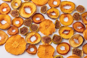 slices of dried persimmon, peach, plum and figs on a white background. dried fruits. eco.
