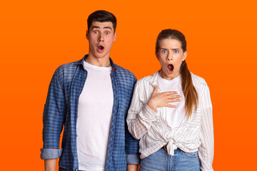 Young surprised couple with open mouths looking at camera