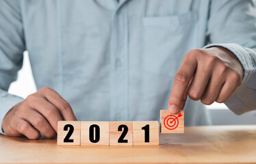 Businessman holding and putting target which print screen on wooden cube block with 2021 , Start...